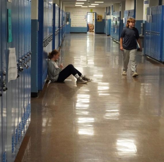 Student Sitting On The Floor Upstairs At Gaudet Middle School